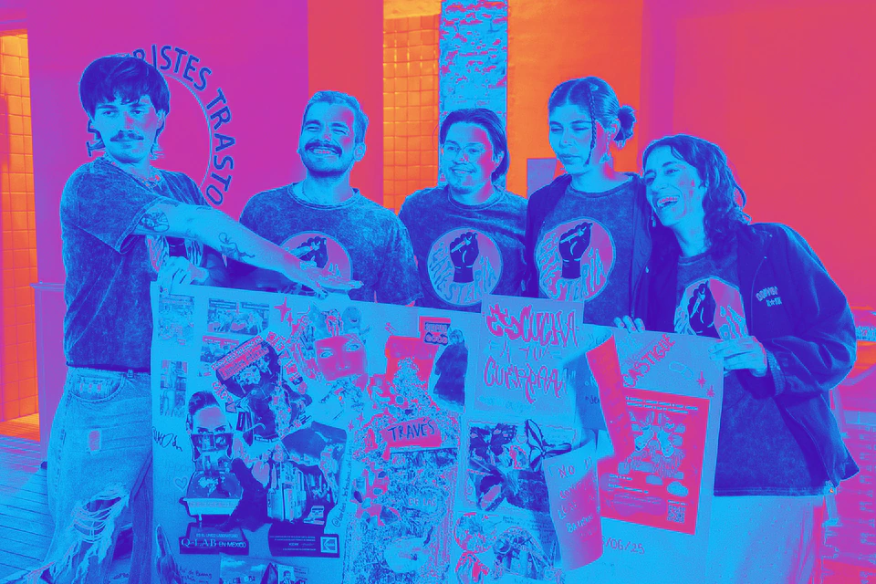 Cinco integrantes de La Testería sonríen detrás de un cartel de collage con la frase «Escucha a tu cuerpa».